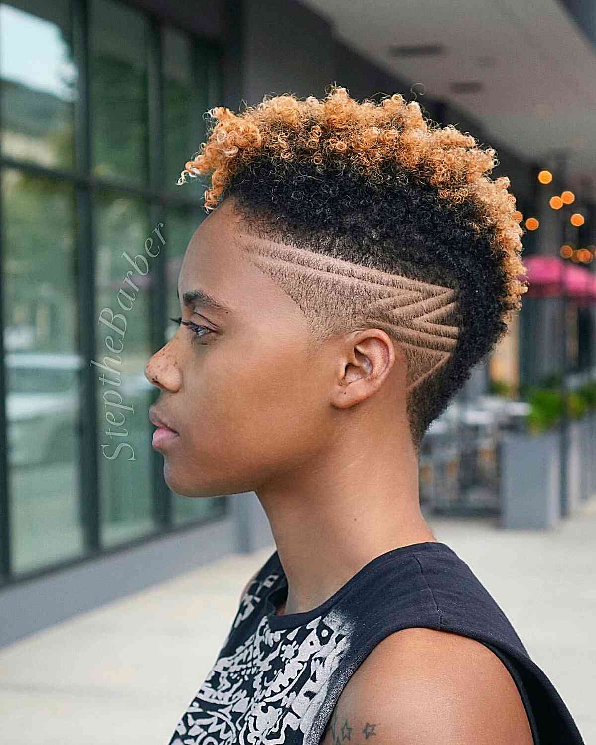 A chic caramel blonde undercut is a fashionable choice for accentuating the volume and texture of your natural curls. The blonde hue complements individuals with a bronze complexion. Adding a shaved design to this natural undercut brings a bold and stylish touch to the look.