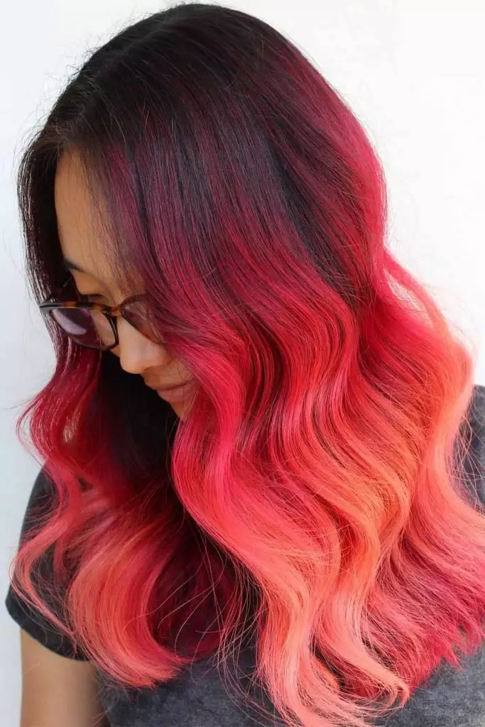 Transitioning from a vibrant red to a soft peach ombre, featuring dark roots