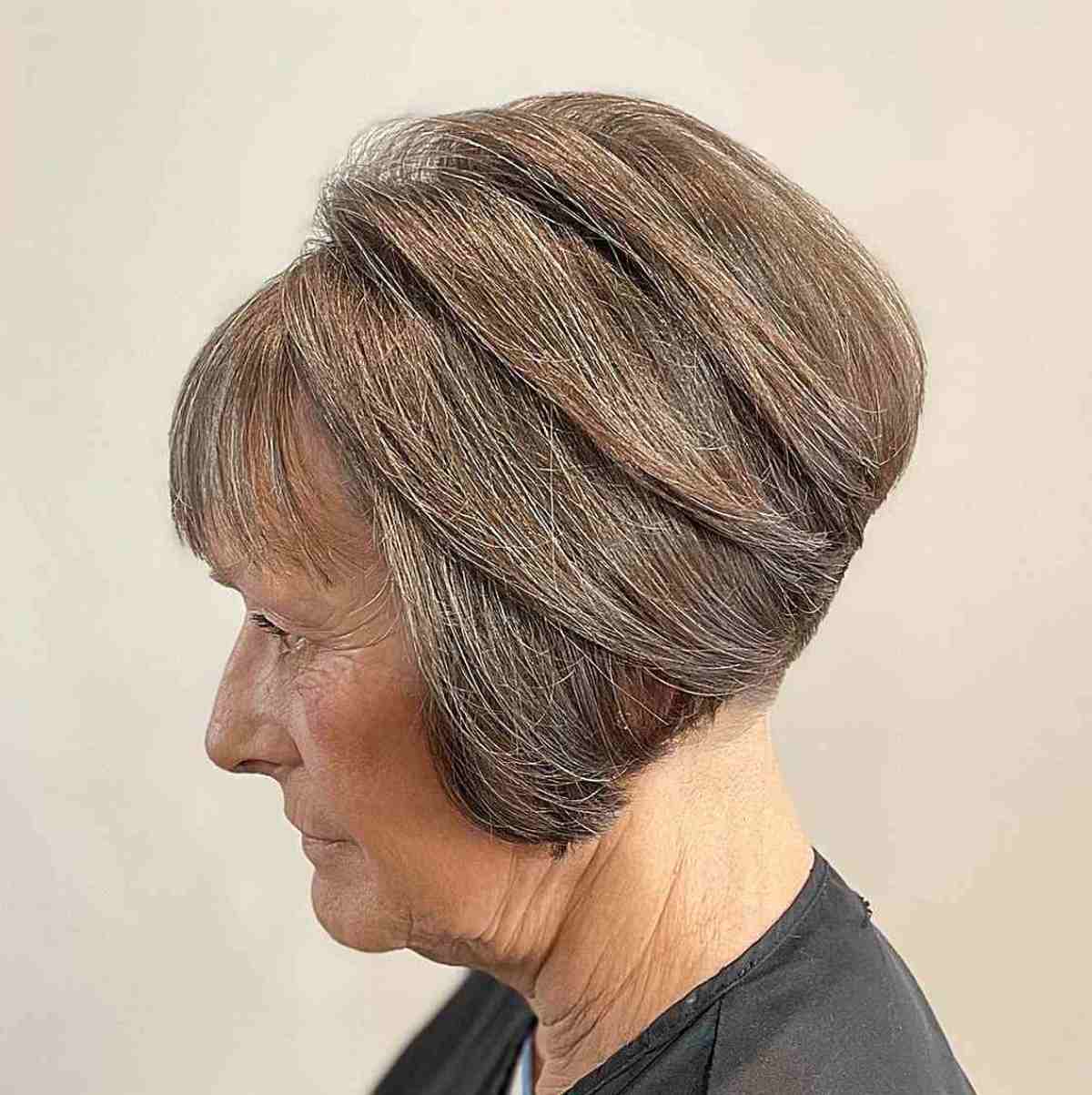 Bob haircut with angled layers, a shaved nape, and wispy bangs